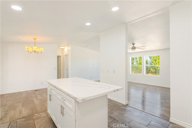 kitchen with white cabinets, light hardwood / wood-style floors, a kitchen island, and decorative light fixtures