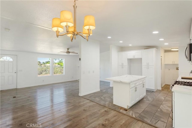 kitchen with white gas stove, a kitchen island, white cabinets, open floor plan, and stainless steel microwave