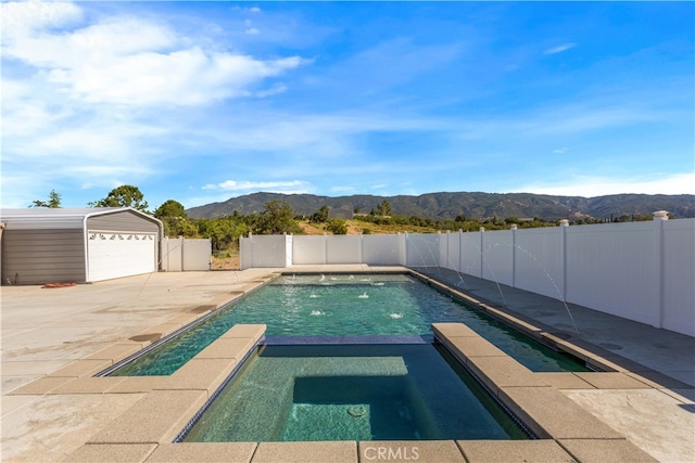 view of pool featuring a mountain view, an outdoor structure, fence, a pool with connected hot tub, and a patio area