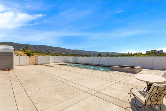 view of pool featuring a fenced backyard, a mountain view, a fenced in pool, and a patio