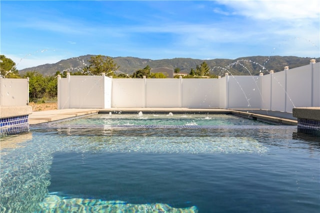 view of swimming pool featuring fence, a mountain view, and a fenced in pool