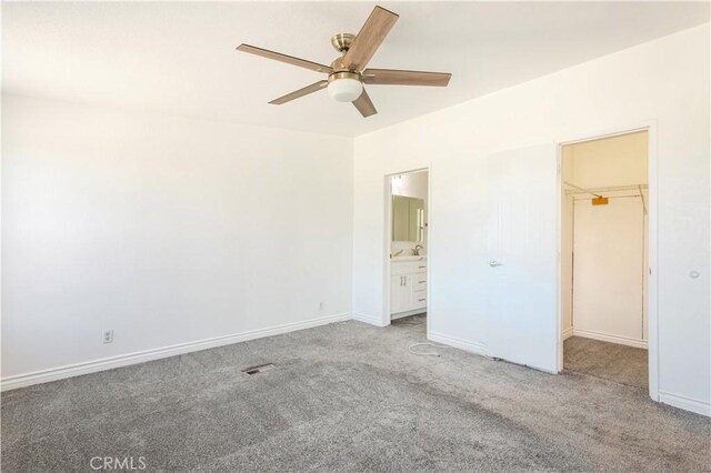 unfurnished bedroom featuring a spacious closet, carpet floors, a closet, ceiling fan, and ensuite bathroom