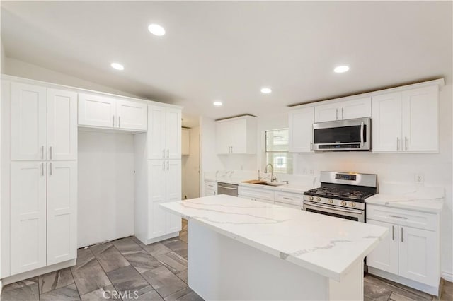 kitchen with stainless steel appliances, a kitchen island, a sink, and white cabinets