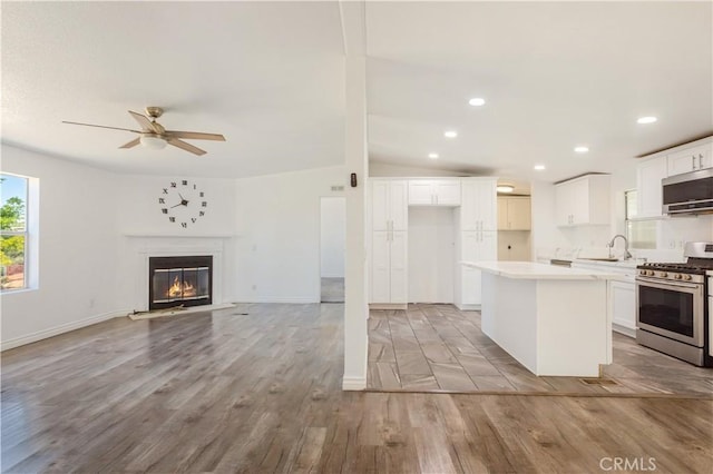 kitchen featuring stainless steel appliances, white cabinets, a kitchen island, and light wood finished floors