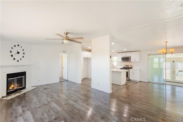 unfurnished living room featuring a textured ceiling, ceiling fan with notable chandelier, lofted ceiling, and hardwood / wood-style flooring