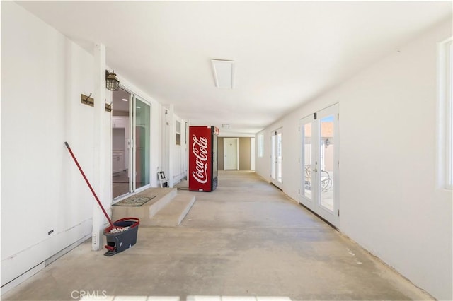 hall featuring unfinished concrete flooring and french doors