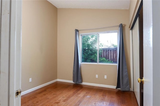 empty room with wood-type flooring and a textured ceiling