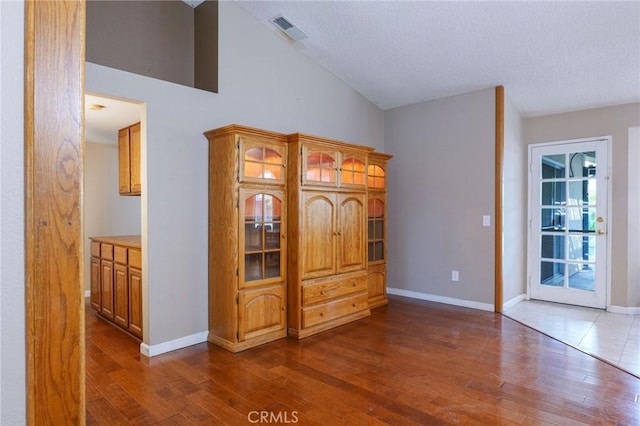 interior space featuring dark hardwood / wood-style floors, a textured ceiling, and high vaulted ceiling