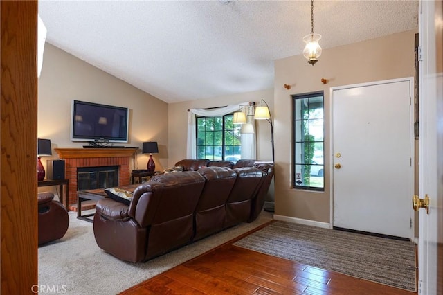 living room featuring a fireplace, a textured ceiling, hardwood / wood-style flooring, and lofted ceiling