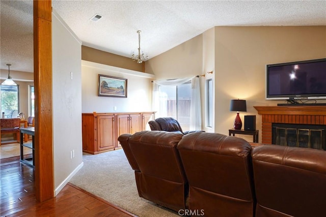 living room featuring plenty of natural light, wood-type flooring, lofted ceiling, and a notable chandelier