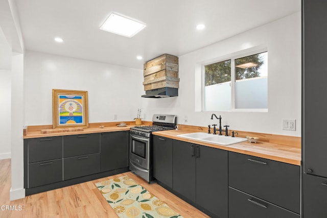 kitchen featuring light hardwood / wood-style floors, gas stove, sink, extractor fan, and wood counters