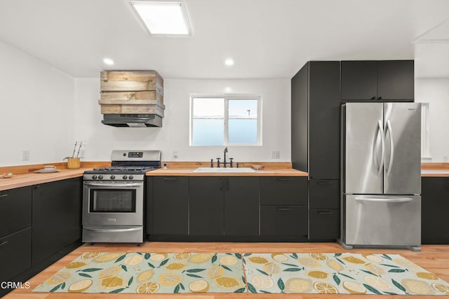 kitchen featuring stainless steel appliances, sink, extractor fan, and light hardwood / wood-style flooring