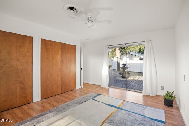 unfurnished bedroom with ceiling fan, multiple closets, light hardwood / wood-style flooring, and access to outside