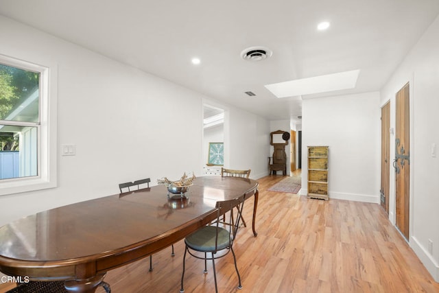 dining room featuring light hardwood / wood-style flooring and a skylight