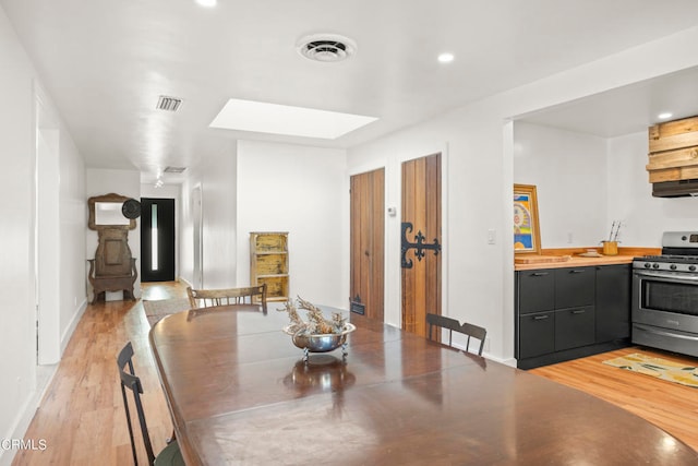 dining room with light wood-type flooring and a skylight