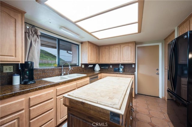 kitchen featuring sink, black refrigerator, backsplash, light brown cabinetry, and stainless steel dishwasher