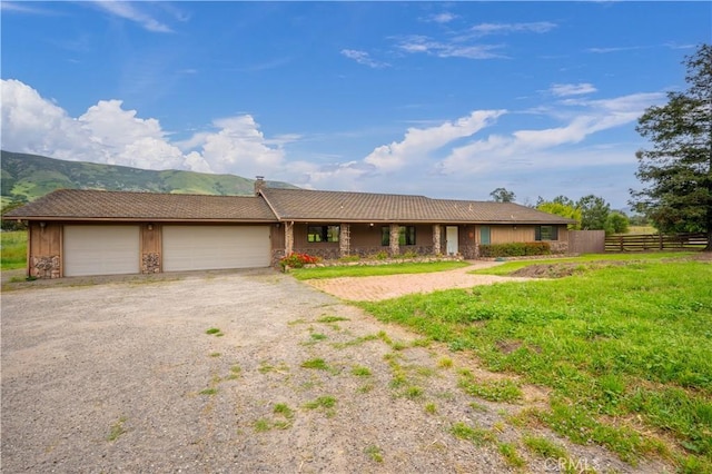 single story home featuring a mountain view, a garage, and a front lawn