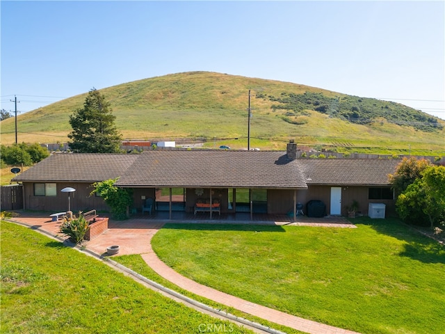 rear view of property with a mountain view, a lawn, and a patio area