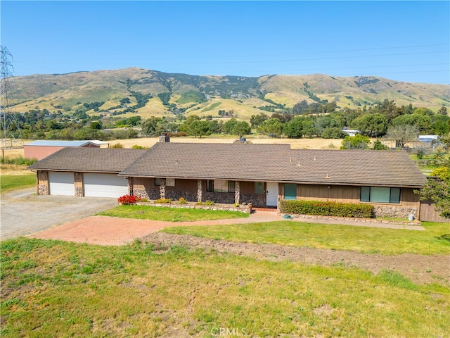 ranch-style house with a garage, a mountain view, and a front yard