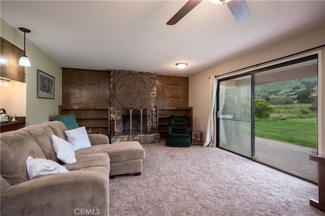 carpeted living room featuring a fireplace and ceiling fan