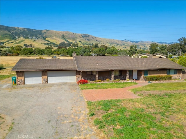 ranch-style house with a garage, a mountain view, and a front lawn