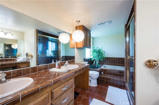 bathroom featuring a relaxing tiled tub, vanity, tile patterned floors, and toilet