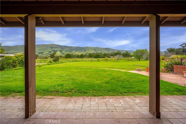 exterior space featuring a rural view, a mountain view, a lawn, and a patio