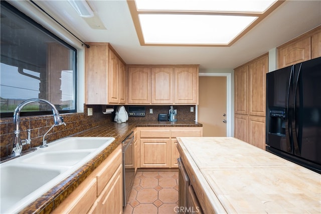 kitchen with black fridge, sink, stainless steel dishwasher, and light brown cabinetry