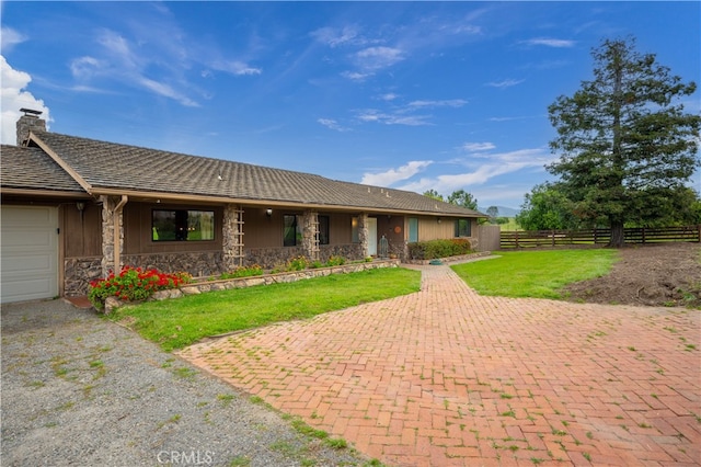 ranch-style home featuring a garage and a front lawn