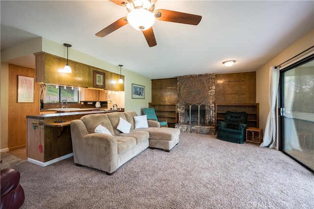 carpeted living room featuring plenty of natural light, a fireplace, and sink