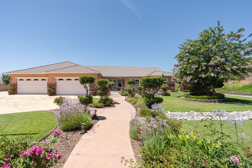 view of front of home featuring a tile roof, stucco siding, an attached garage, driveway, and a front lawn