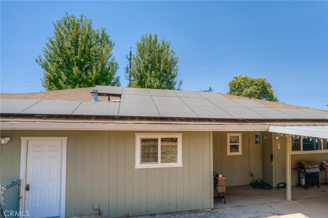 rear view of property featuring a patio area and solar panels