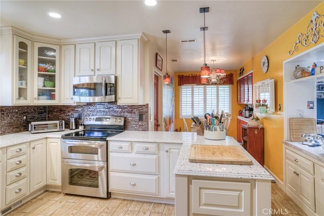 kitchen with tasteful backsplash, a center island, pendant lighting, stainless steel appliances, and light stone countertops