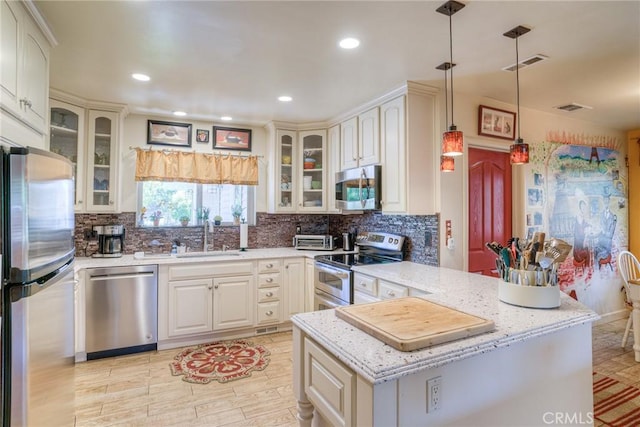 kitchen featuring sink, hanging light fixtures, stainless steel appliances, light stone countertops, and kitchen peninsula