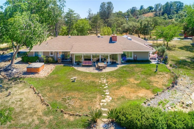 back of property featuring a lawn, a hot tub, and a patio