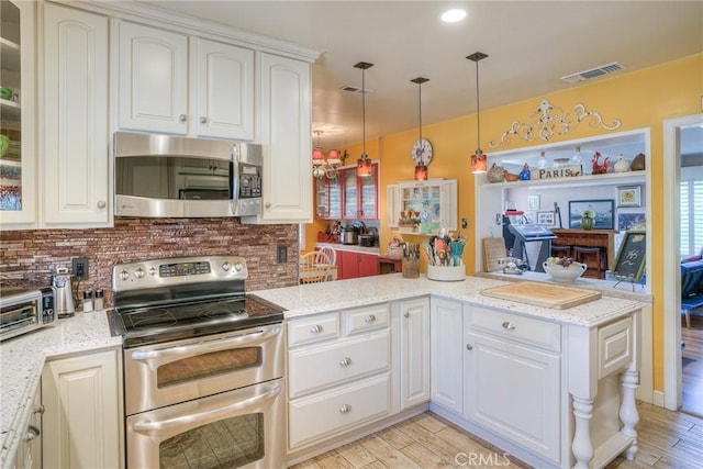 kitchen featuring white cabinetry, decorative light fixtures, appliances with stainless steel finishes, kitchen peninsula, and light stone countertops