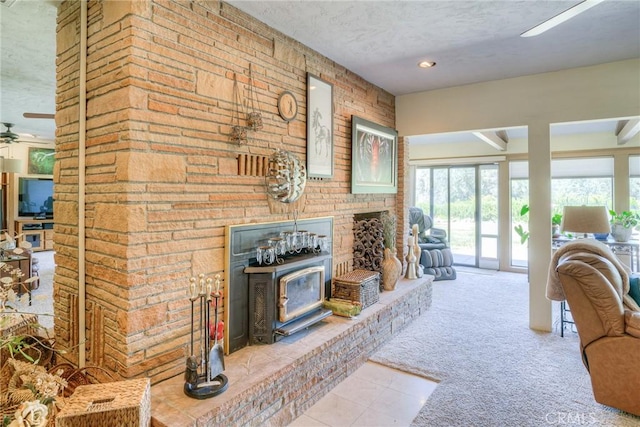 living room with ceiling fan, a healthy amount of sunlight, a textured ceiling, and a wood stove