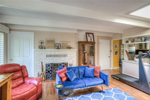 living room featuring beamed ceiling, a fireplace, hardwood / wood-style floors, and a textured ceiling