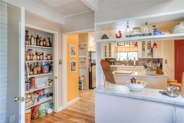 interior space featuring sink, a textured ceiling, stainless steel appliances, light hardwood / wood-style floors, and backsplash