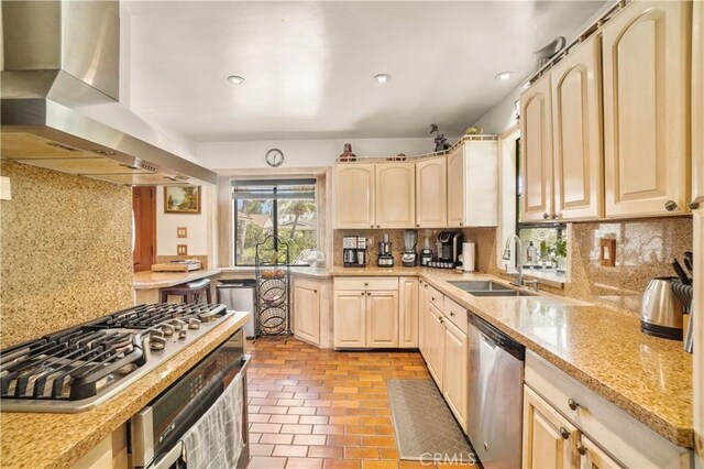 kitchen featuring wall chimney exhaust hood, sink, appliances with stainless steel finishes, and tasteful backsplash