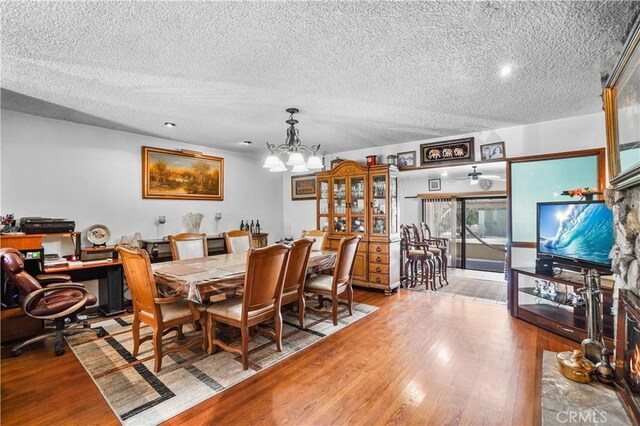 dining space with a chandelier, light hardwood / wood-style floors, and a textured ceiling