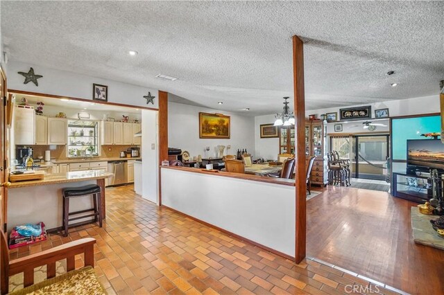 kitchen with dishwasher, a textured ceiling, a chandelier, and light hardwood / wood-style flooring