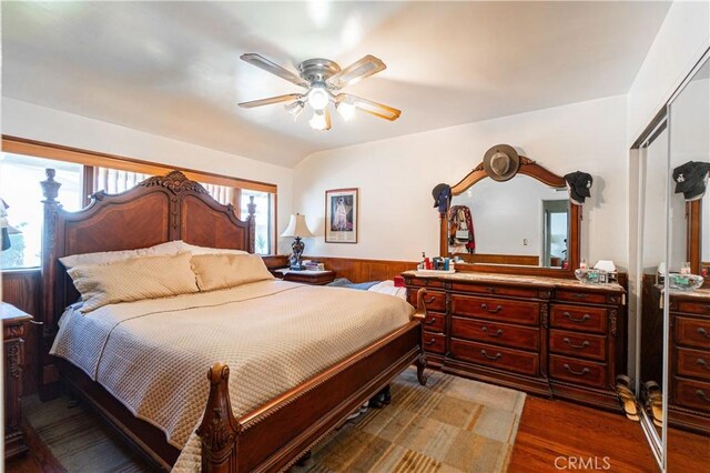 bedroom with ceiling fan, a closet, wood walls, and dark hardwood / wood-style floors