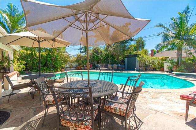 view of swimming pool featuring a patio, a diving board, and a storage shed