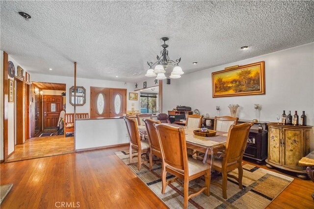 dining area with a chandelier, a textured ceiling, and light hardwood / wood-style flooring