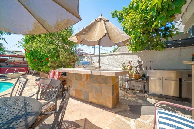 view of patio featuring a grill, a bar, and exterior kitchen