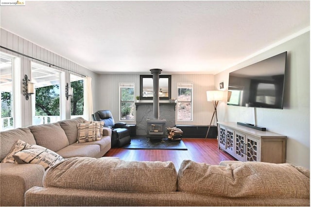 living room featuring dark hardwood / wood-style flooring, a wood stove, and plenty of natural light