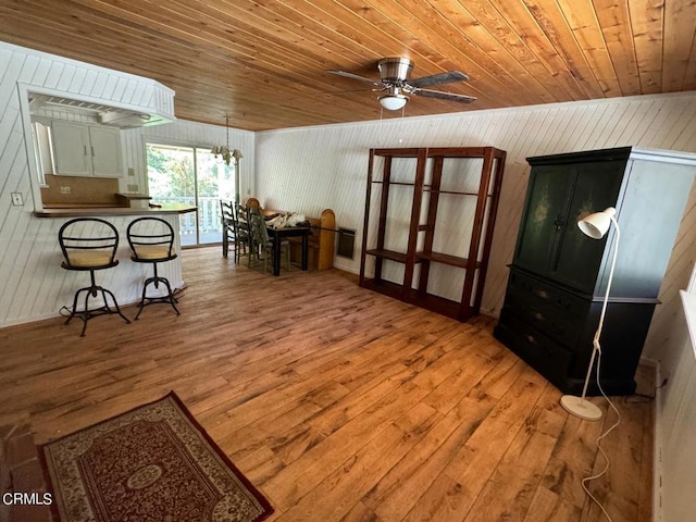 interior space featuring wooden walls, wood ceiling, ceiling fan with notable chandelier, and hardwood / wood-style flooring