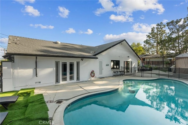 rear view of house featuring fence, stucco siding, french doors, a shingled roof, and a patio area