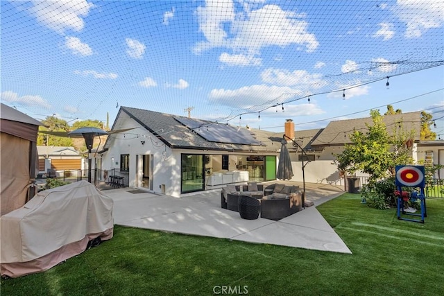 back of house featuring a patio, a fenced backyard, an outdoor living space, roof mounted solar panels, and a yard